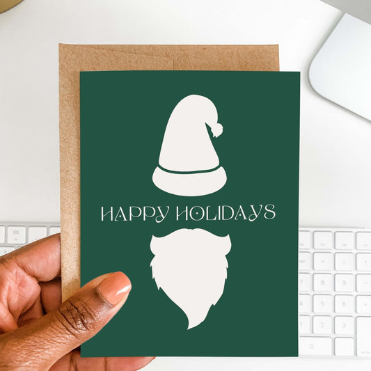 Hand holding minimalist Santa holiday greeting card with green background and kraft envelope