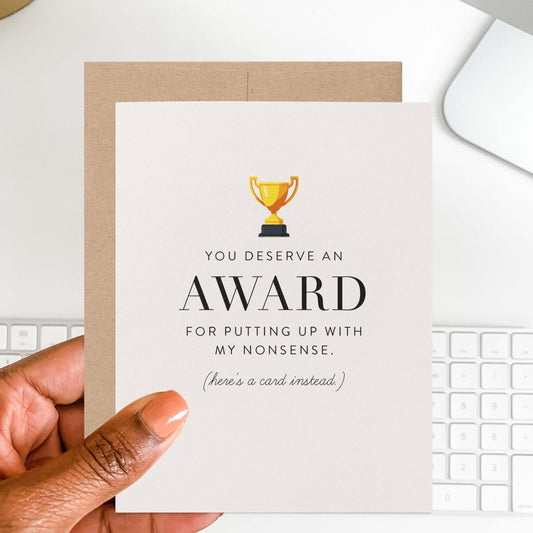 Hand holding humorous award card with gold trophy design