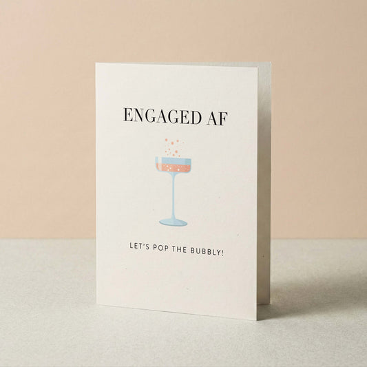 Greeting card with 'ENGAGED AF' text and champagne glass illustration on a beige background