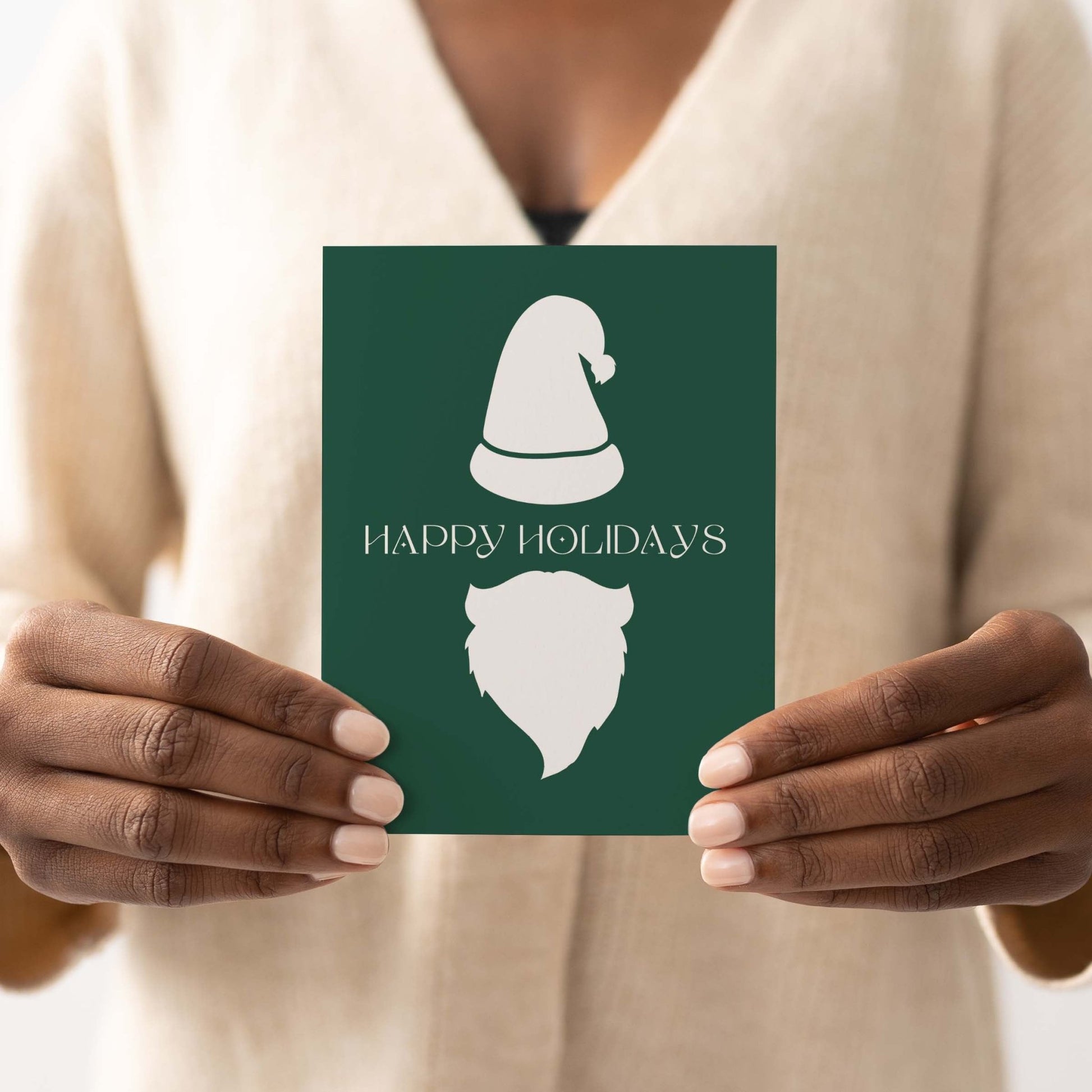 Modern holiday greeting card featuring minimalist Santa design, held by person in beige sweater.