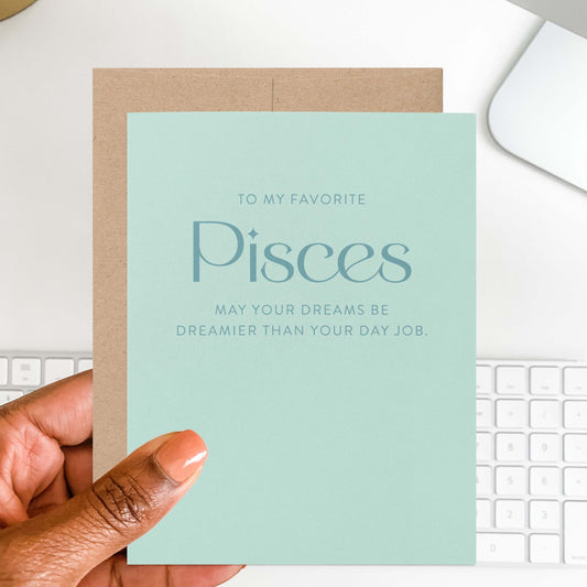 Hand holding modern Pisces zodiac birthday card in soft aqua