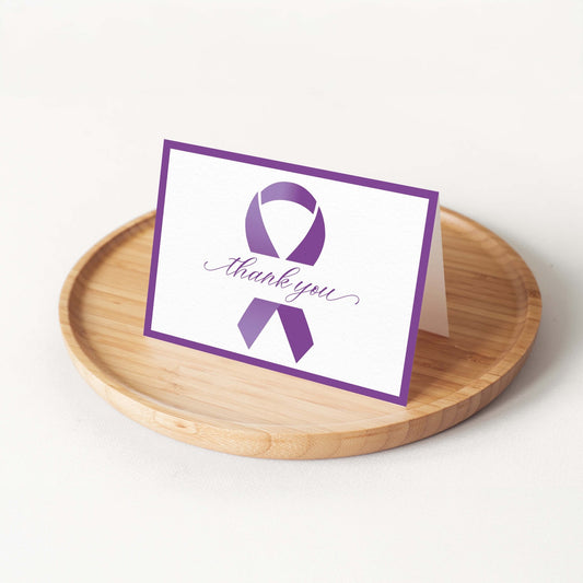 Purple Ribbon Thank You Card by Blú Rose displayed folded on a round bamboo tray