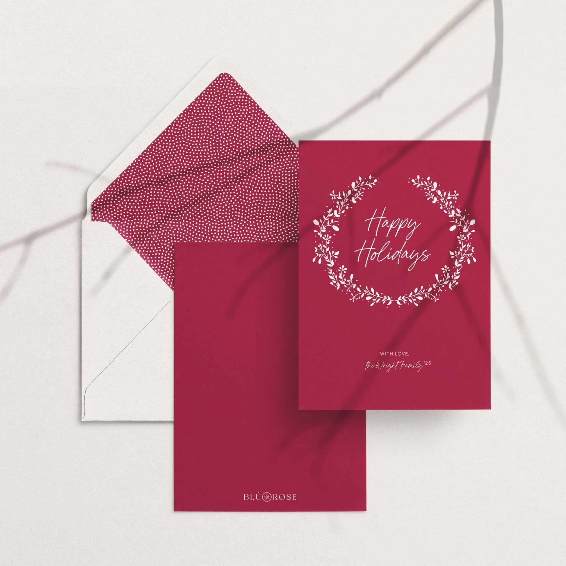 Personalized holiday card with matching red patterned envelope liner, flat lay on white background.