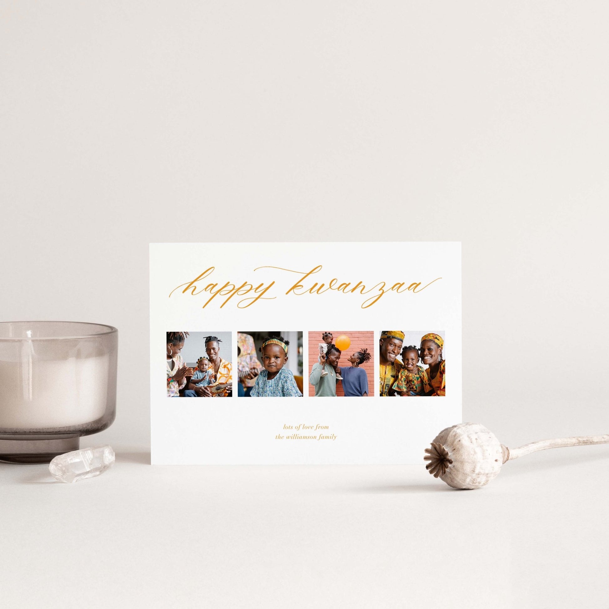 Elegant personalized holiday card with four photos and gold script, styled on table with candle.
