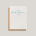 A white greeting card with the phrase 'TO THE BEST dog mom I KNOW' in light blue and gray text, shown with a brown kraft envelope on a light gray background.