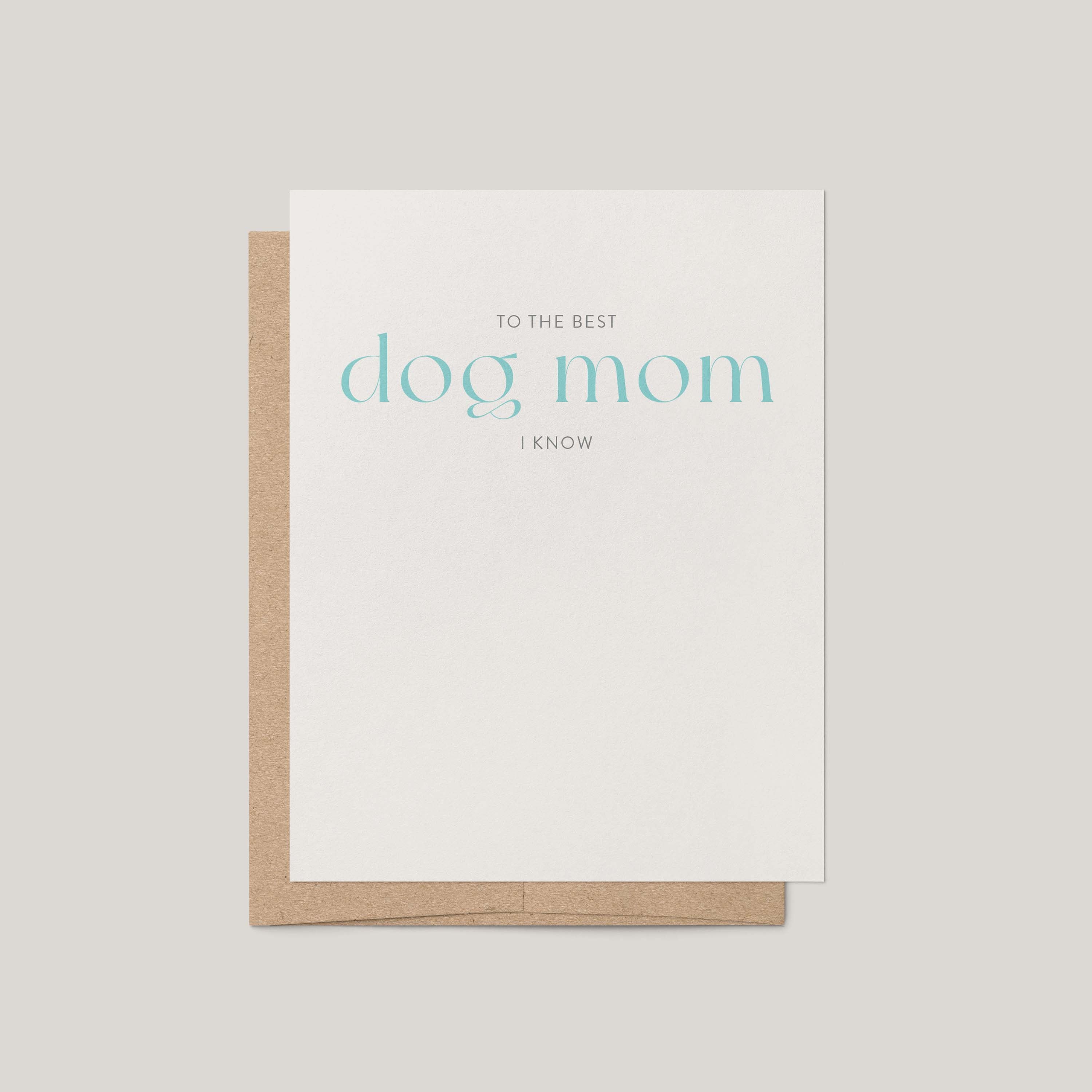 A white greeting card with the phrase 'TO THE BEST dog mom I KNOW' in light blue and gray text, shown with a brown kraft envelope on a light gray background.