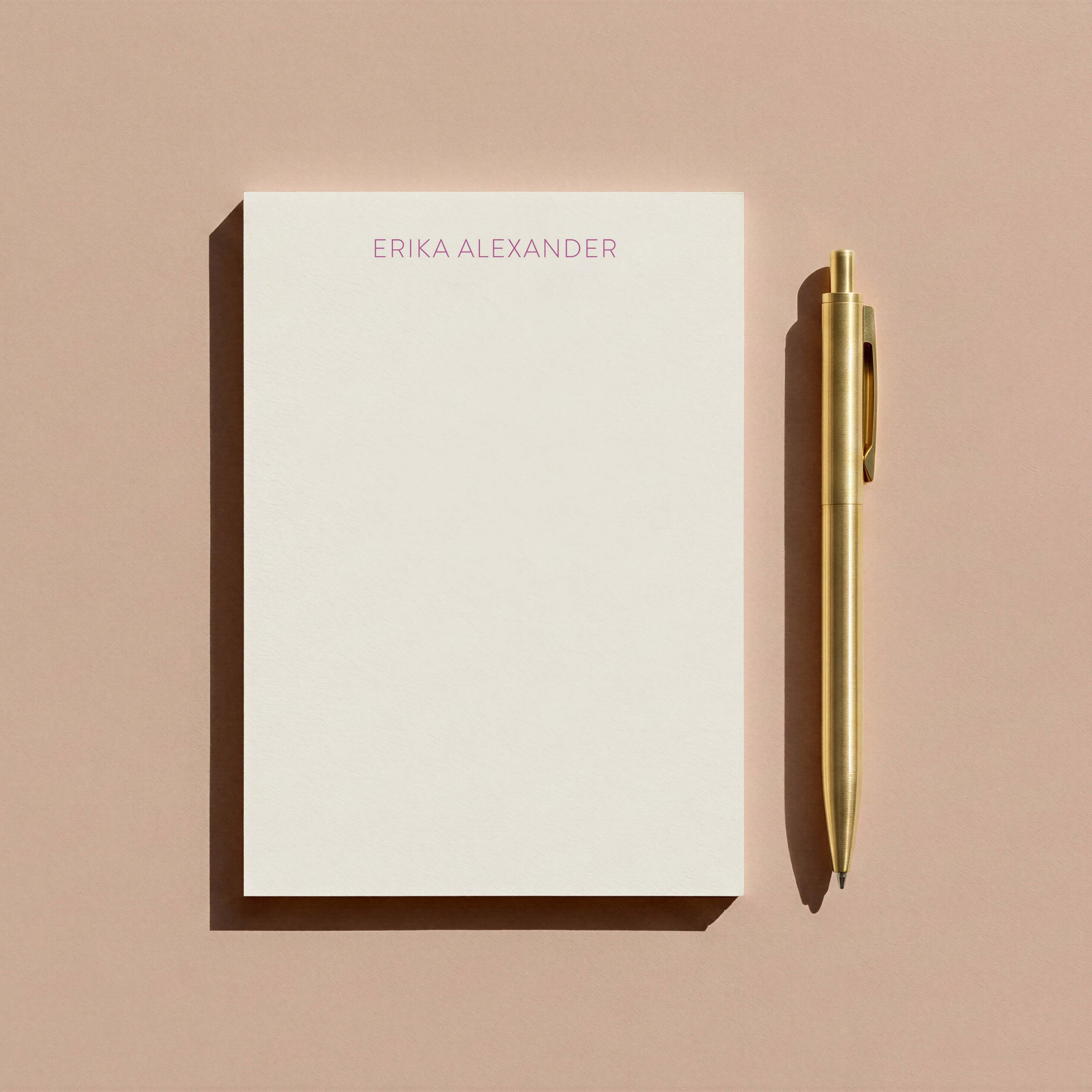 Erika stationery set by Blú Rose, cream notepad personalized 'Erika Alexander' in lavender, photographed with a gold pen on a mauve background