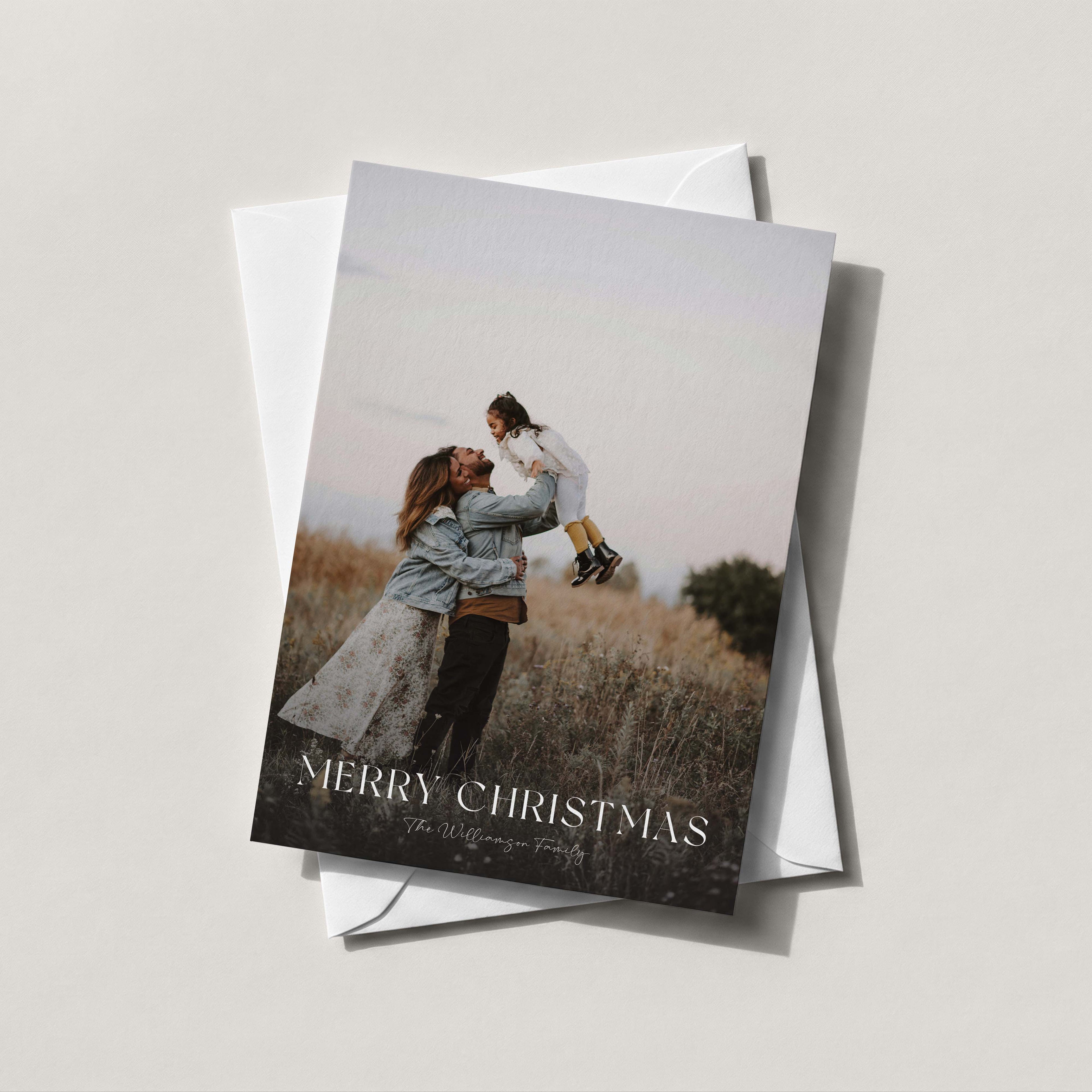 Golden Hour photo holiday card with a full-bleed family photo and MERRY CHRISTMAS in white, on a white envelope