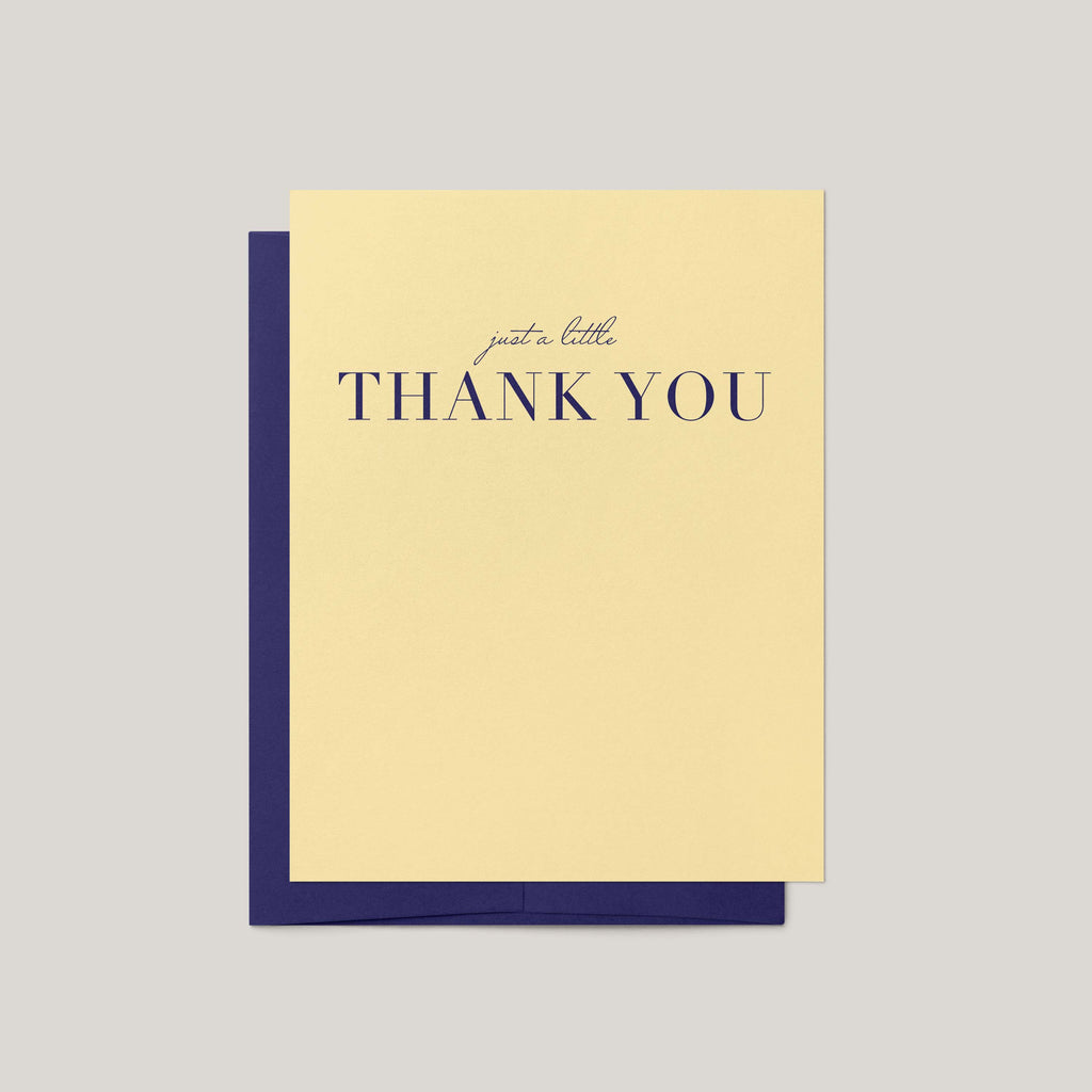 A yellow-colored thank-you card with navy blue text reading 'just a little THANK YOU', shown with a matching navy blue envelope on a light gray background.