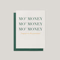 A white greeting card with a dark green envelope behind it, printed with the phrase 'MO' MONEY MO' MONEY MO' MONEY' in dark green serif letters and 'Congrats on the promotion!' in small gold script below, on a light gray background.