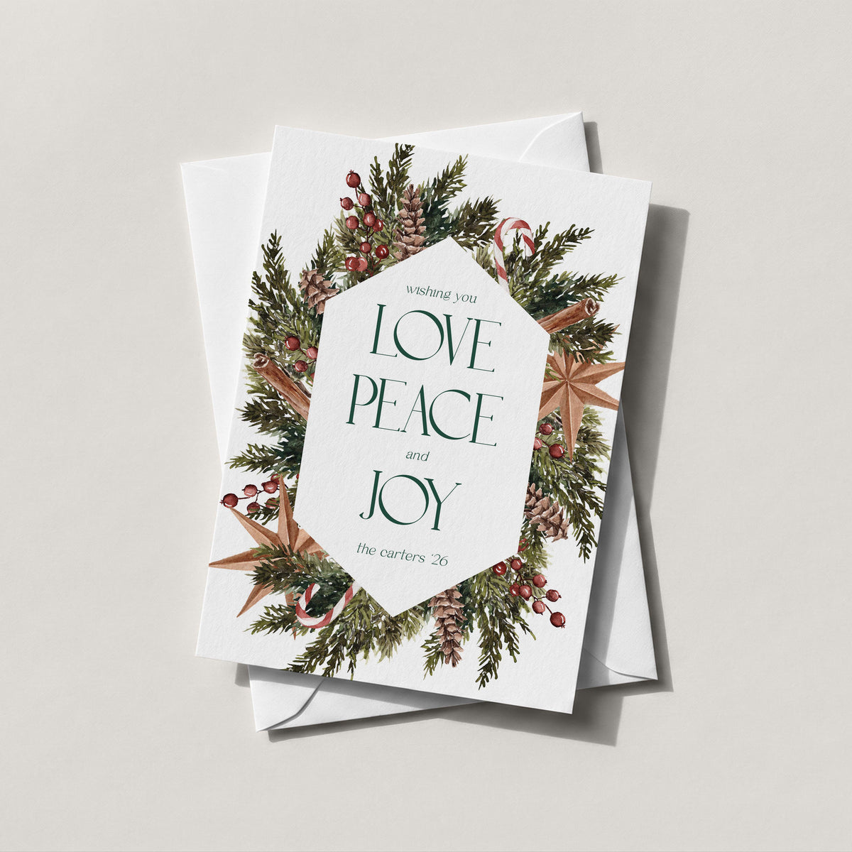 Winter Wreath holiday card with an evergreen, pinecone and berry wreath framing LOVE PEACE and JOY in green lettering