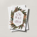 Winter Wreath holiday card with an evergreen, pinecone and berry wreath framing LOVE PEACE and CHEER in burgundy lettering