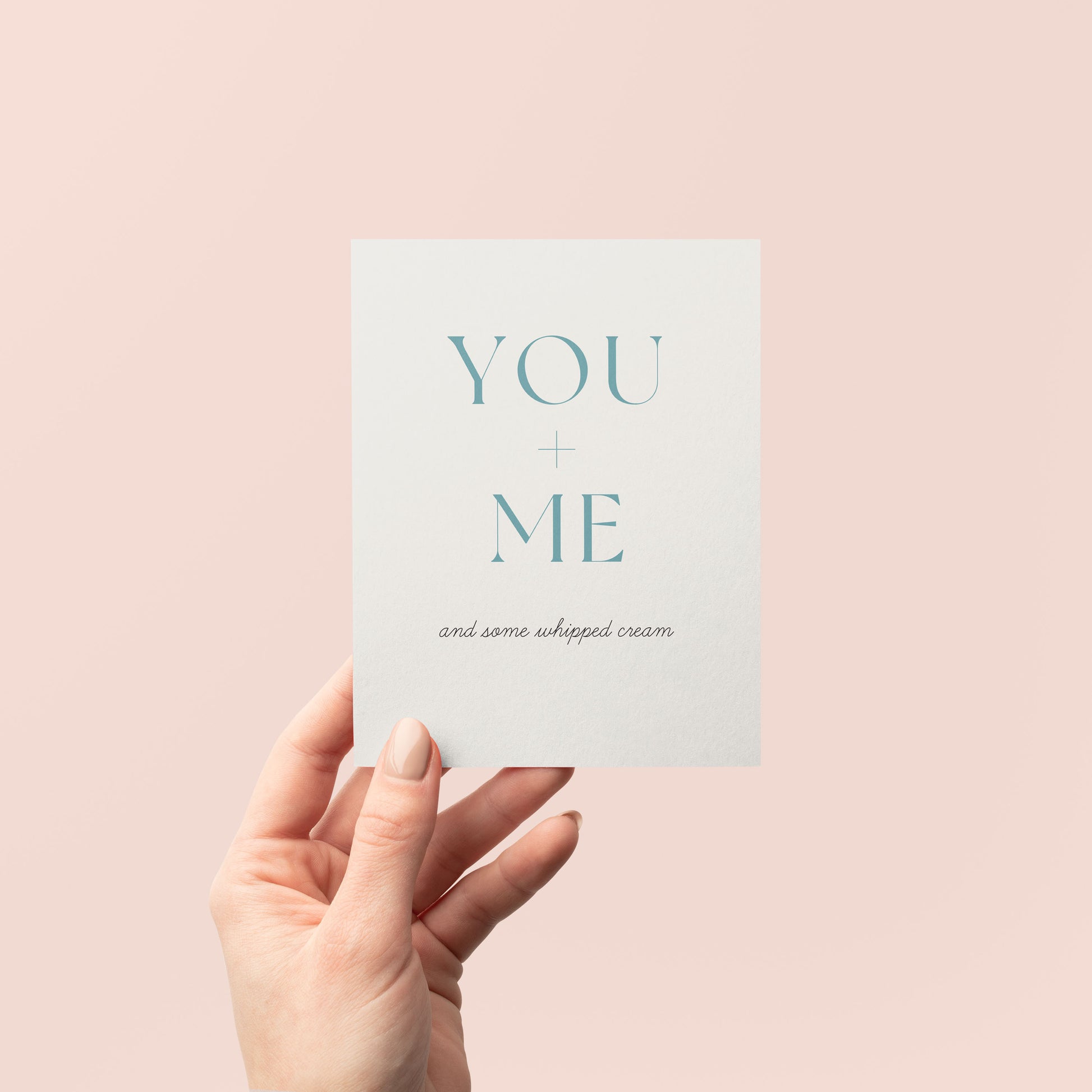 Hand holding a card with 'YOU + ME and some whipped cream' text on a pink background