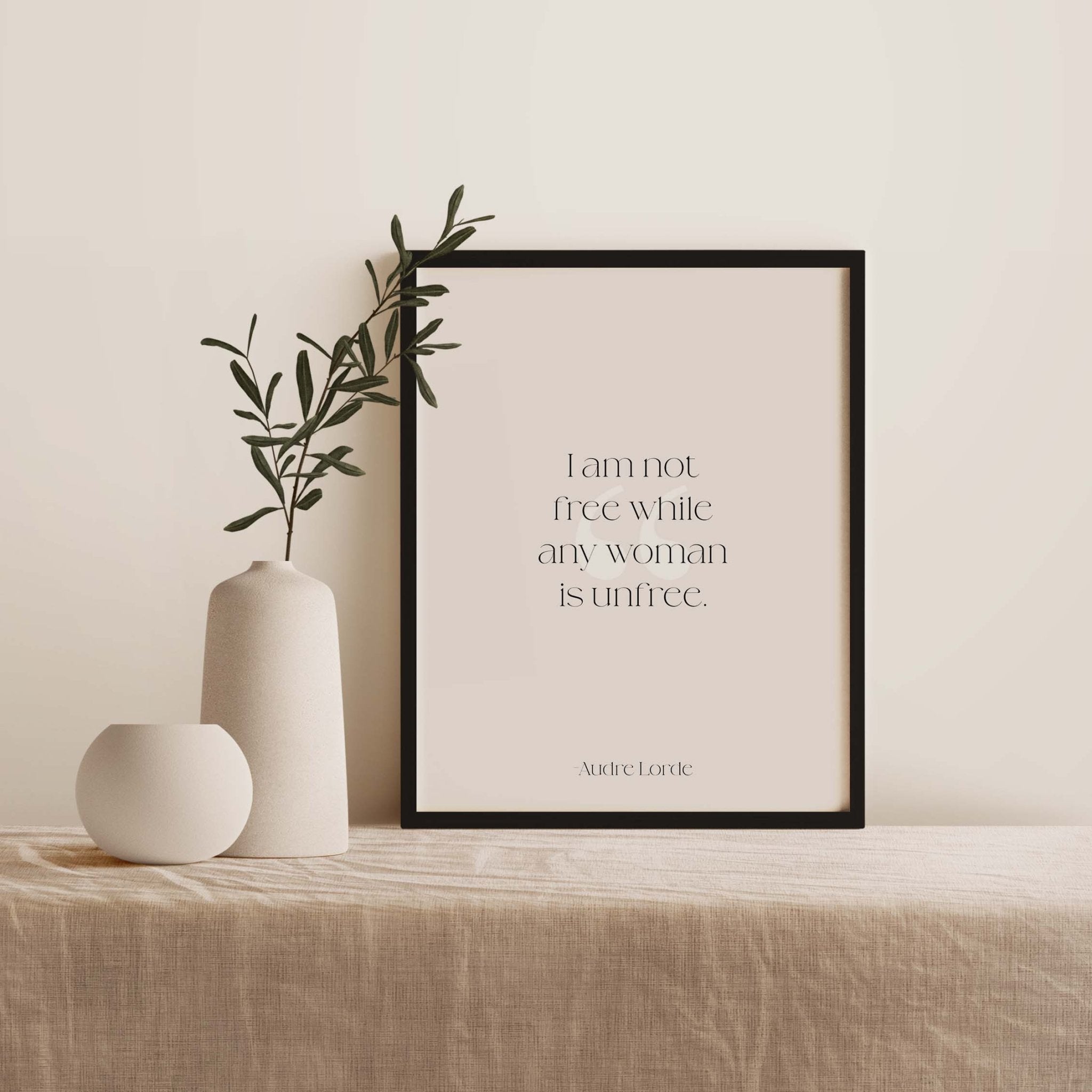 Black framed Audre Lorde quote print on textured console table with ceramic vase