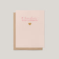 A light blush pink greeting card with a brown kraft envelope behind it, featuring the phrase 'IF "because I said so" WAS A PERSON.' in pink lettering and a small gold foil heart on a neutral gray background.