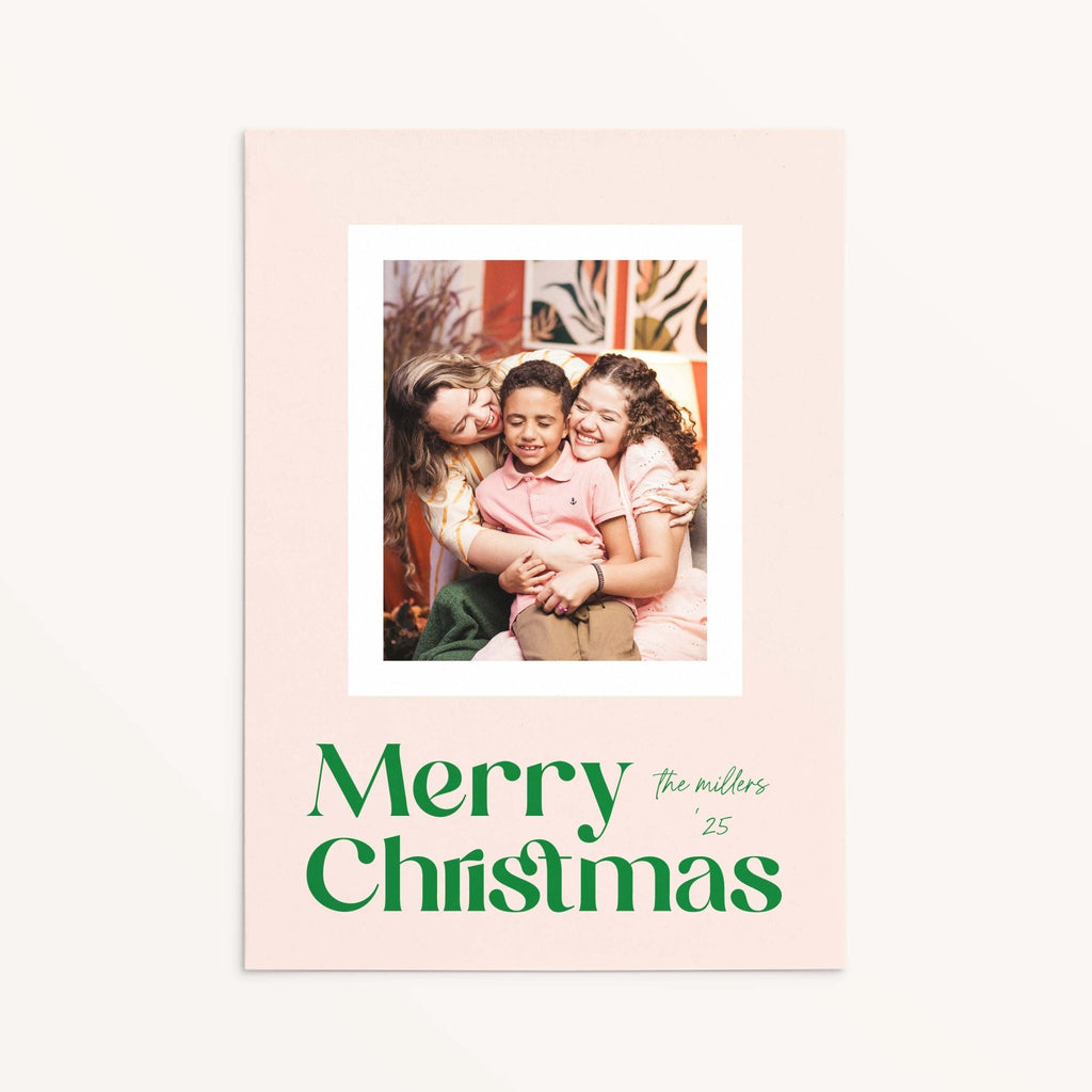 Blush Frame Merry Christmas photo card with modern green serif font and family photo in white border.