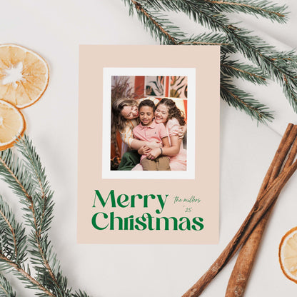 Blush Frame Merry Christmas holiday photo card styled flat lay with greenery, pinecones, and cinnamon sticks.