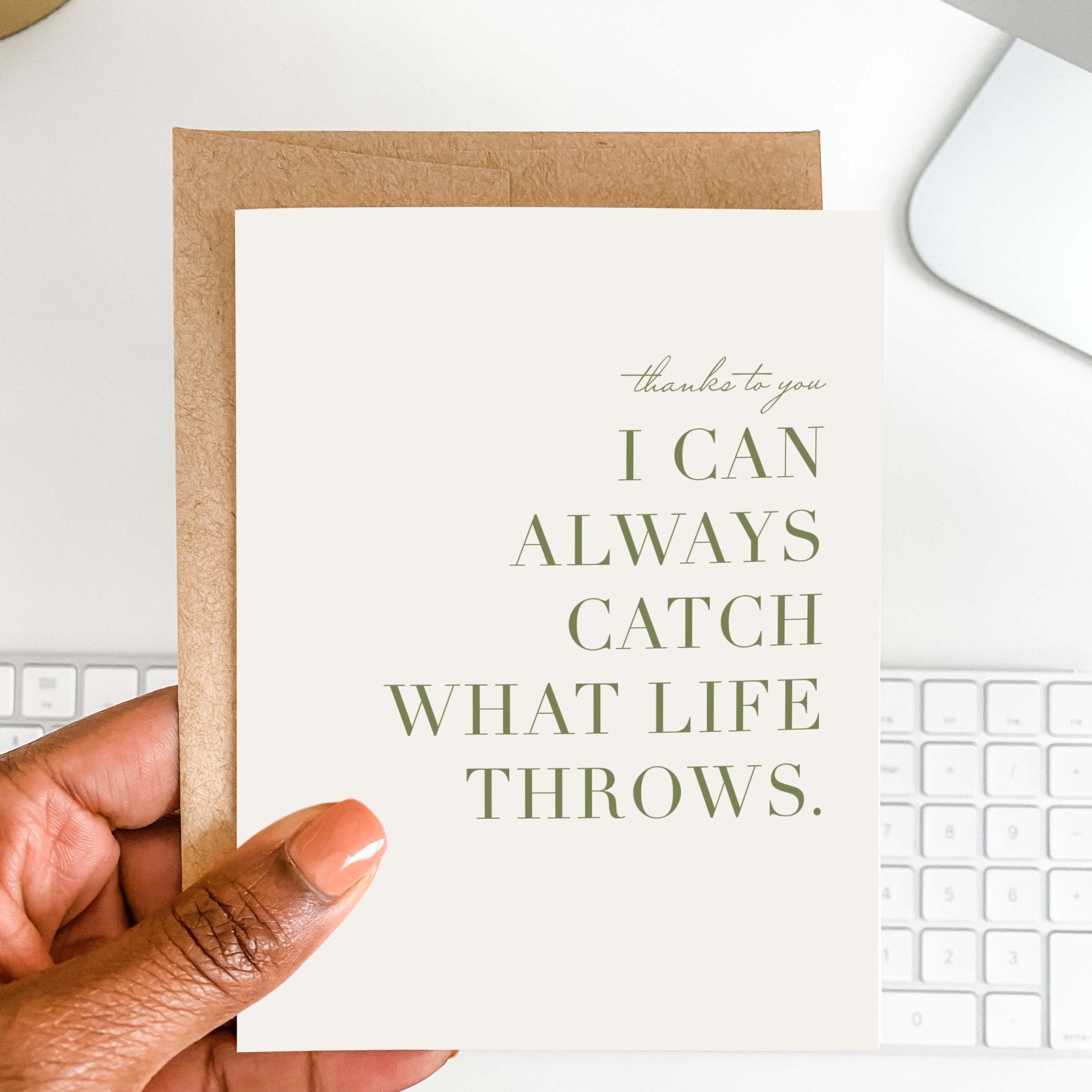 Catch What Life Throws thank you card by Blú Rose held in hand over a white desk with keyboard and kraft envelope