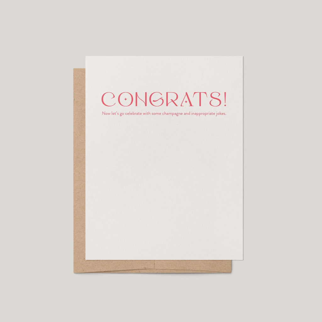 Champagne + Jokes congratulations greeting card by Blú Rose, white card with coral congrats text, shown with kraft envelope