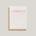 Champagne + Jokes congratulations greeting card by Blú Rose, white card with coral congrats text, shown with kraft envelope
