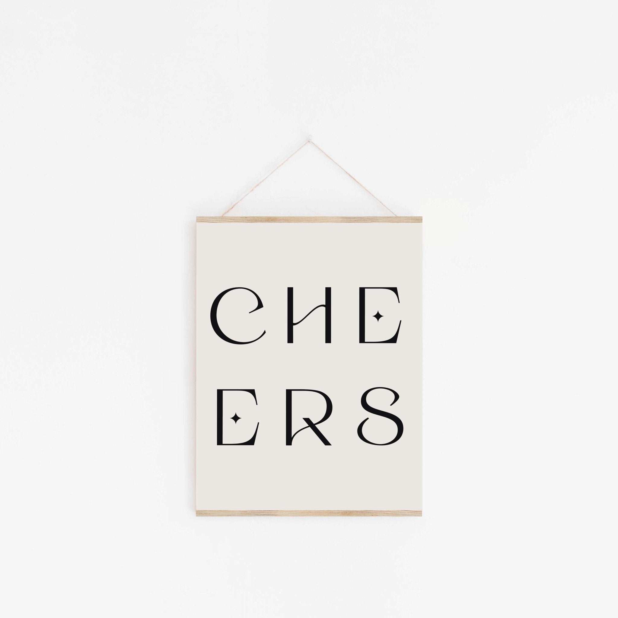 Minimal “CHEERS” typography art print with black lettering hanging on a white wall with wooden poster rails.