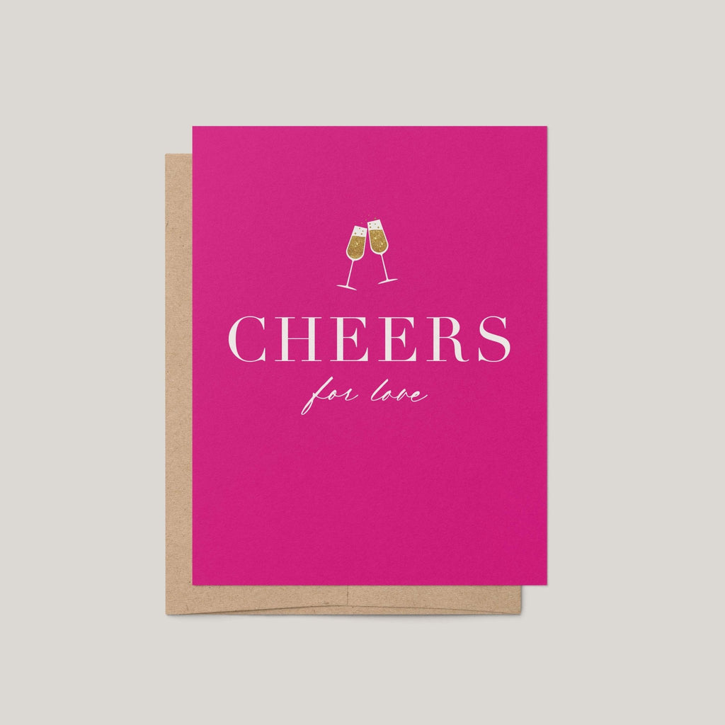A bright pink greeting card with a kraft envelope, featuring the text 'CHEERS for love' and a small illustration of two clinking champagne glasses, shown on a light gray background.