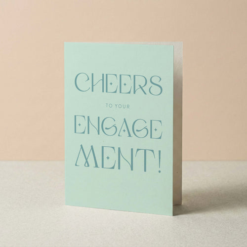 Cheers to Your Engagement congratulations card by Blú Rose standing upright, light blue card with tonal typography on a neutral background
