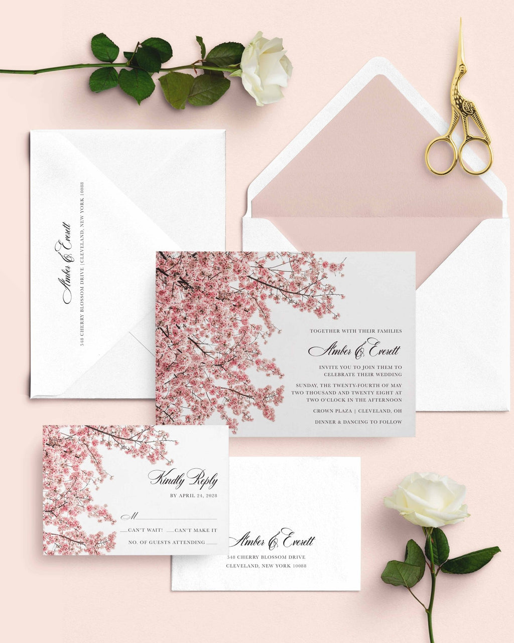 Cherry Blossom wedding invitation suite by Blú Rose, invitation and reply card with pink cherry blossom branches, styled on a blush background with white envelopes, roses, and gold scissors