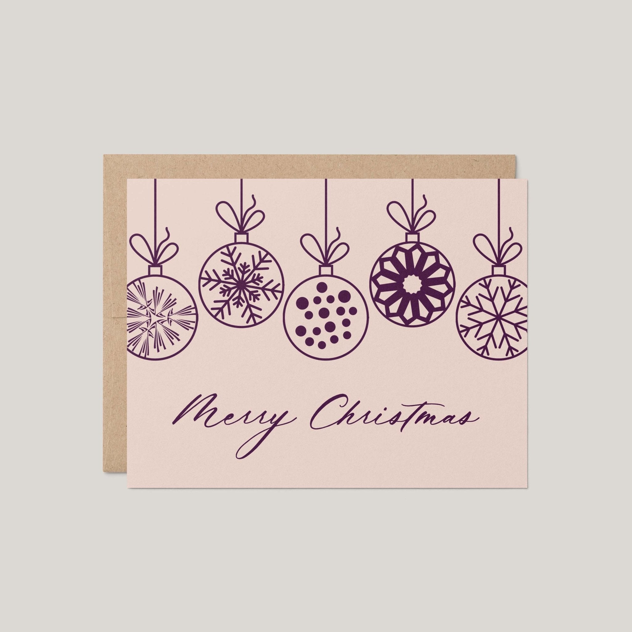 Christmas Ornaments holiday greeting card by Blú Rose, blush card with plum line-drawn hanging ornaments and Merry Christmas script, shown with kraft envelope