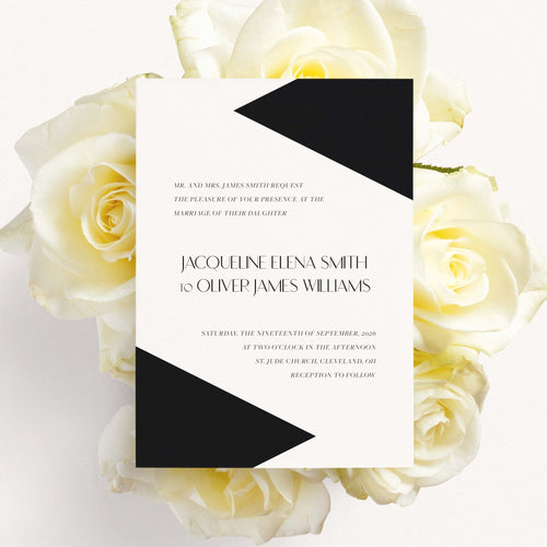 Classy Geo wedding invitation by Blú Rose, white card with bold black geometric triangles and modern serif names, styled on white roses