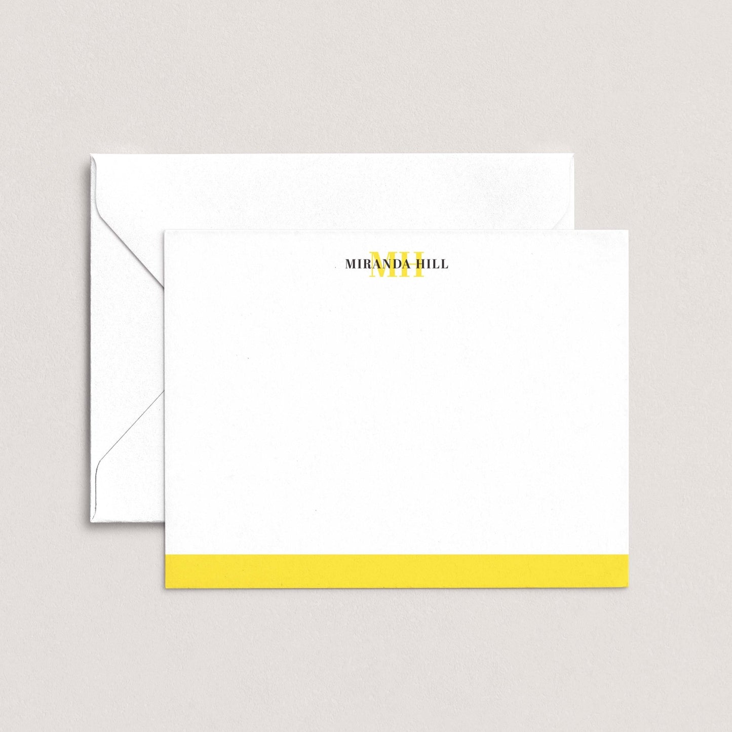 A white envelope with a yellow stripe and a blank card with the text "MIRANDA HILL" printed on it.