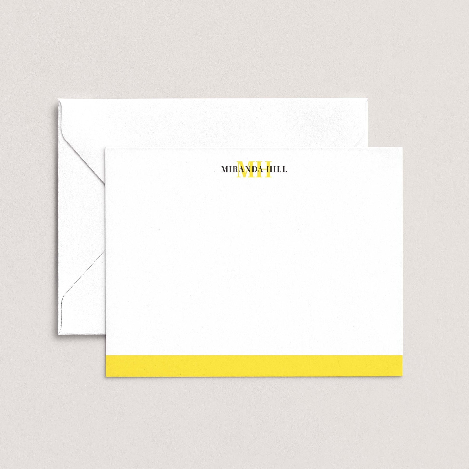 A white envelope with a yellow stripe and a blank card with the text "MIRANDA HILL" printed on it.