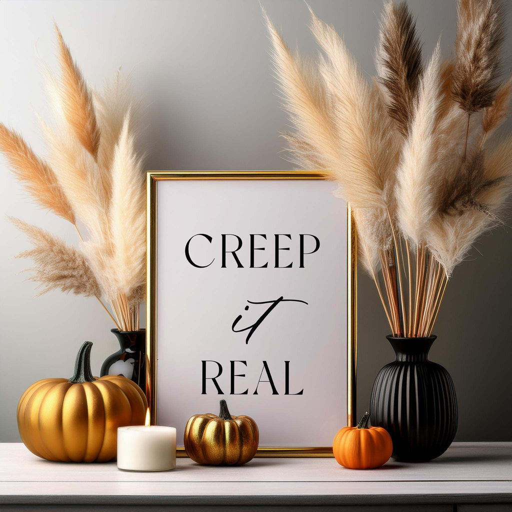 “Creep it Real” art print displayed with pampas grass, small pumpkins, and neutral fall decor.