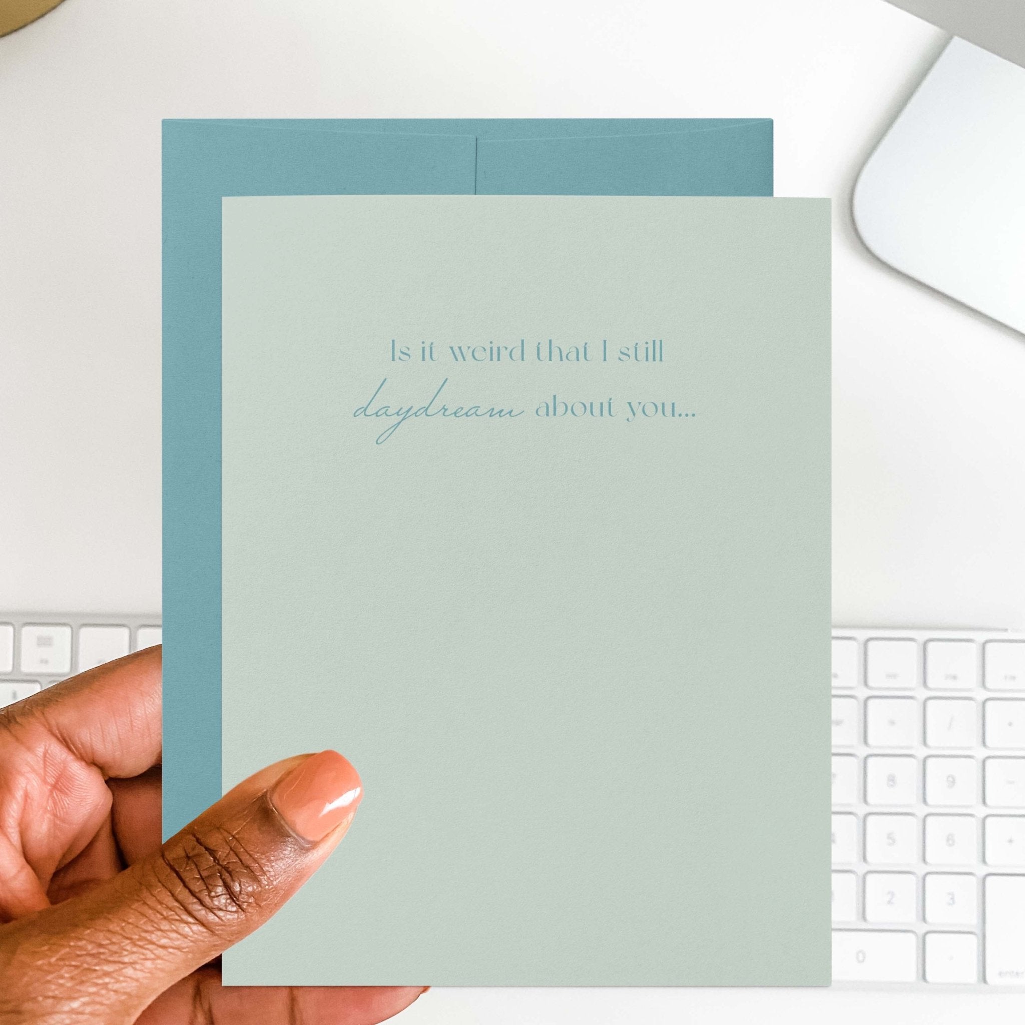 Daydream About You romantic card by Blú Rose held in hand over a white desk with keyboard and blue envelope