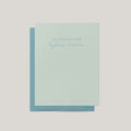 A pale mint green greeting card with a light blue envelope behind it, centered on a light gray background. The card has a small printed phrase in blue script at the top.