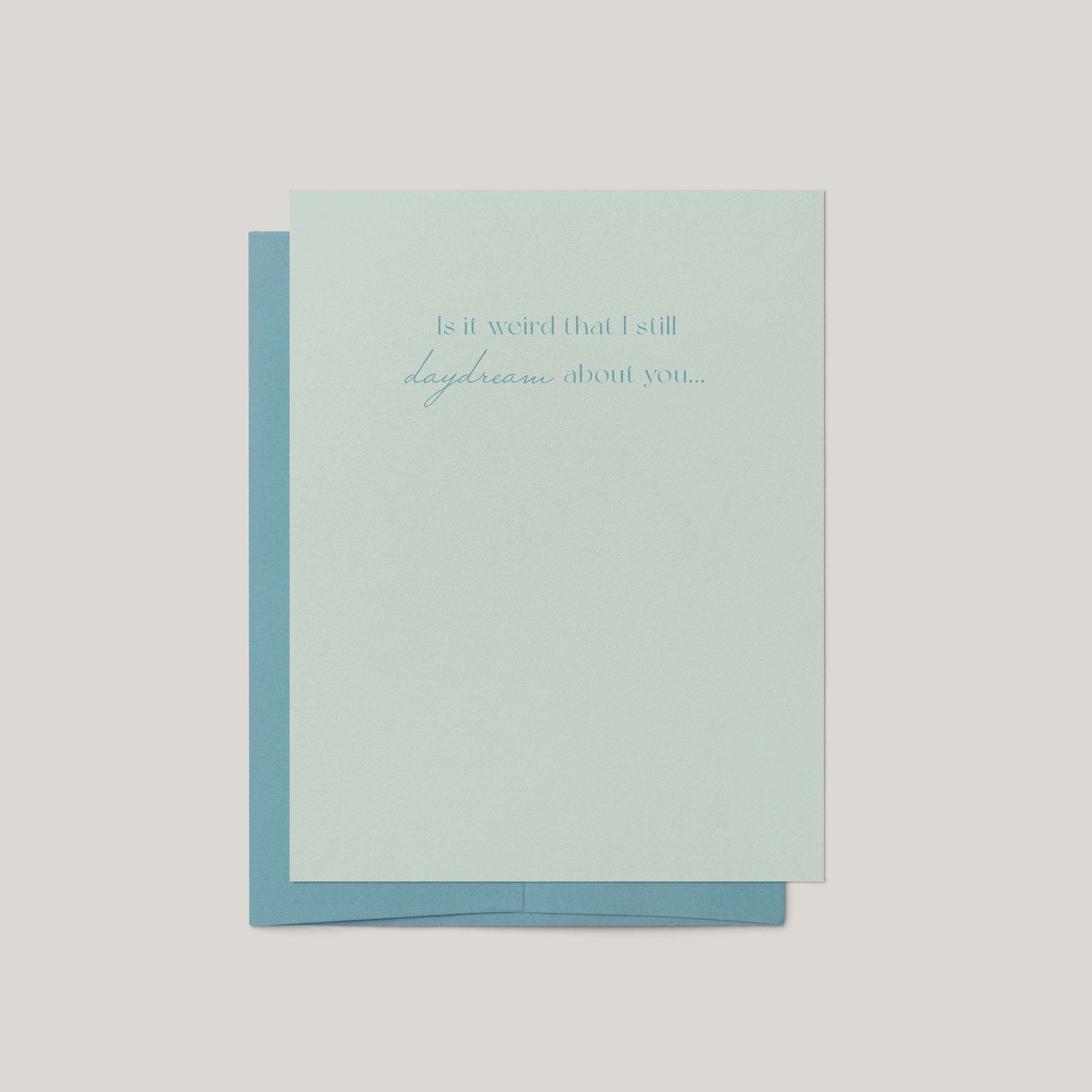 A pale mint green greeting card with a light blue envelope behind it, centered on a light gray background. The card has a small printed phrase in blue script at the top.