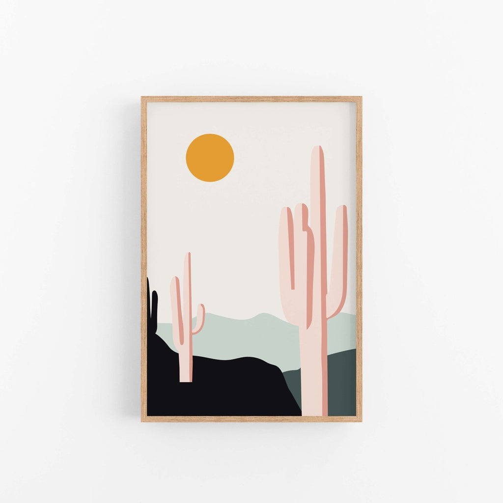 Desert Sunrise Cacti art print by Blú Rose, saguaro cactus desert scene with an orange sun in a light wood frame on a white wall