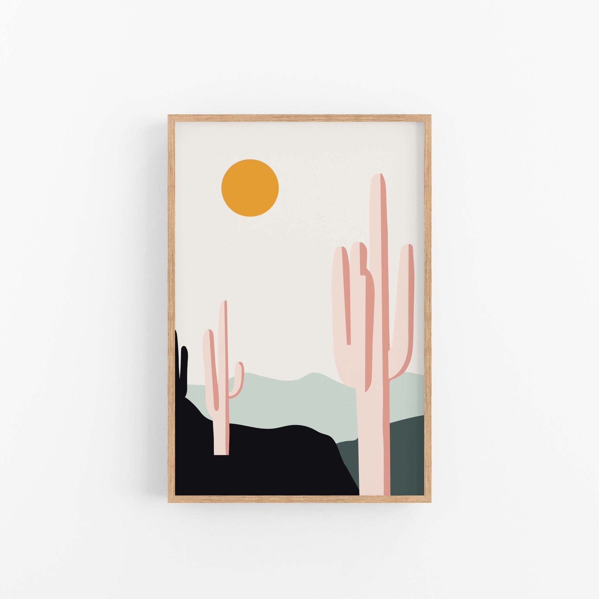 Desert Sunrise Cacti art print by Blú Rose, saguaro cactus desert scene with an orange sun in a light wood frame on a white wall
