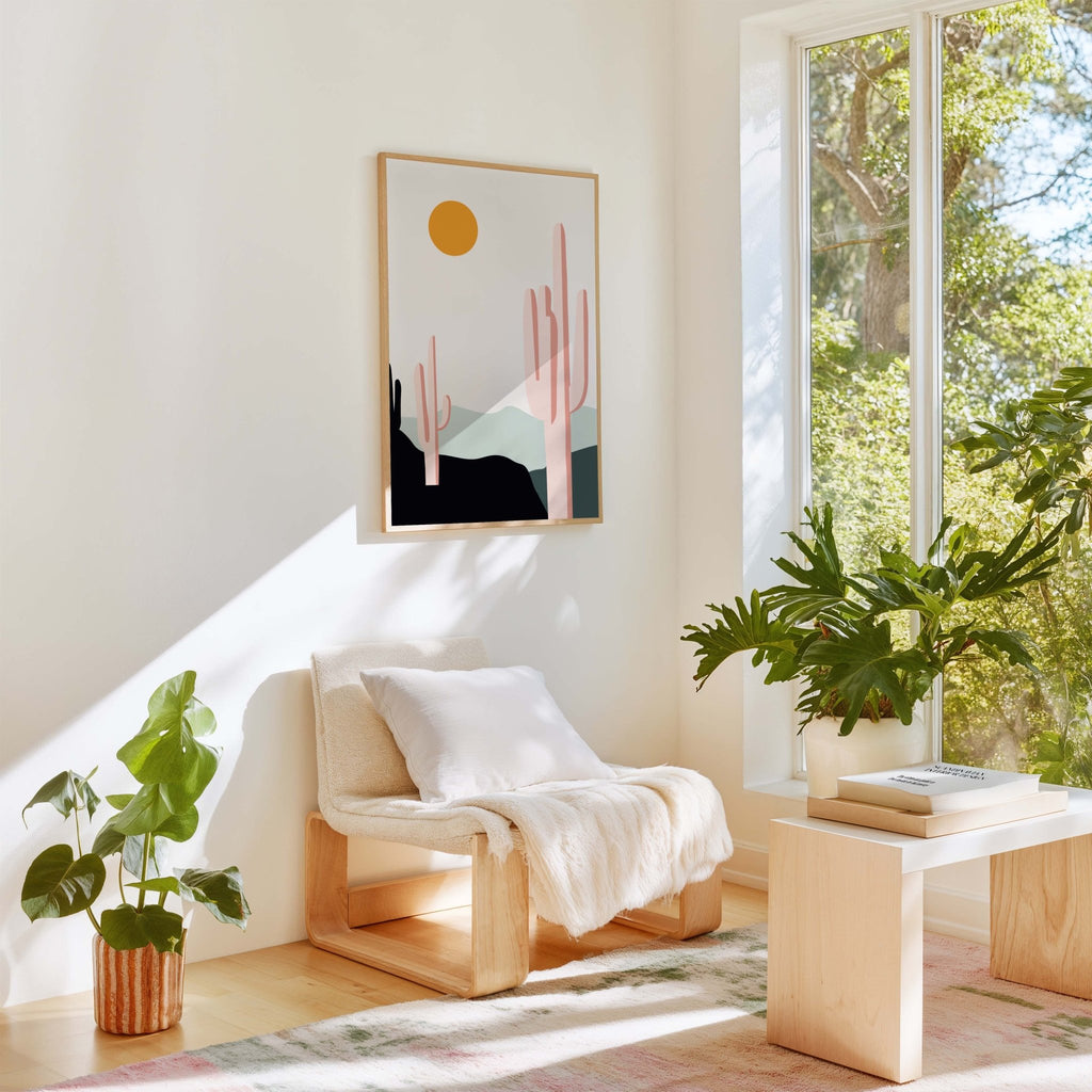 Desert Sunrise Cacti art print by Blú Rose, desert cactus print in a wood frame styled in a bright sunlit room with a chair and plants