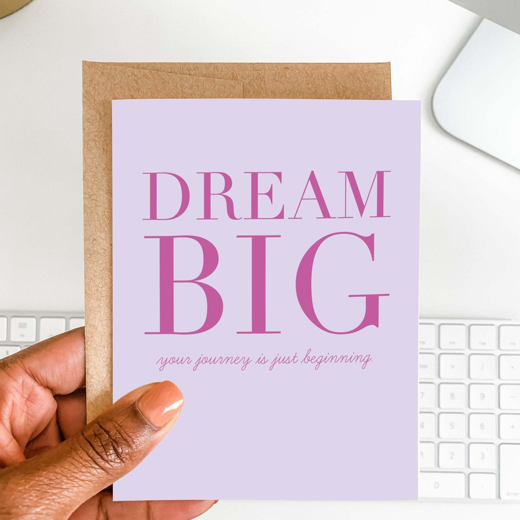 Dream Big graduation card by Blú Rose held in hand over a white desk with keyboard and kraft envelope