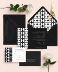 Elizabeth wedding invitation suite by Blú Rose, black invitation and reply card with a white mid-century half-circle pattern, styled on blush with black envelopes, roses, and gold scissors