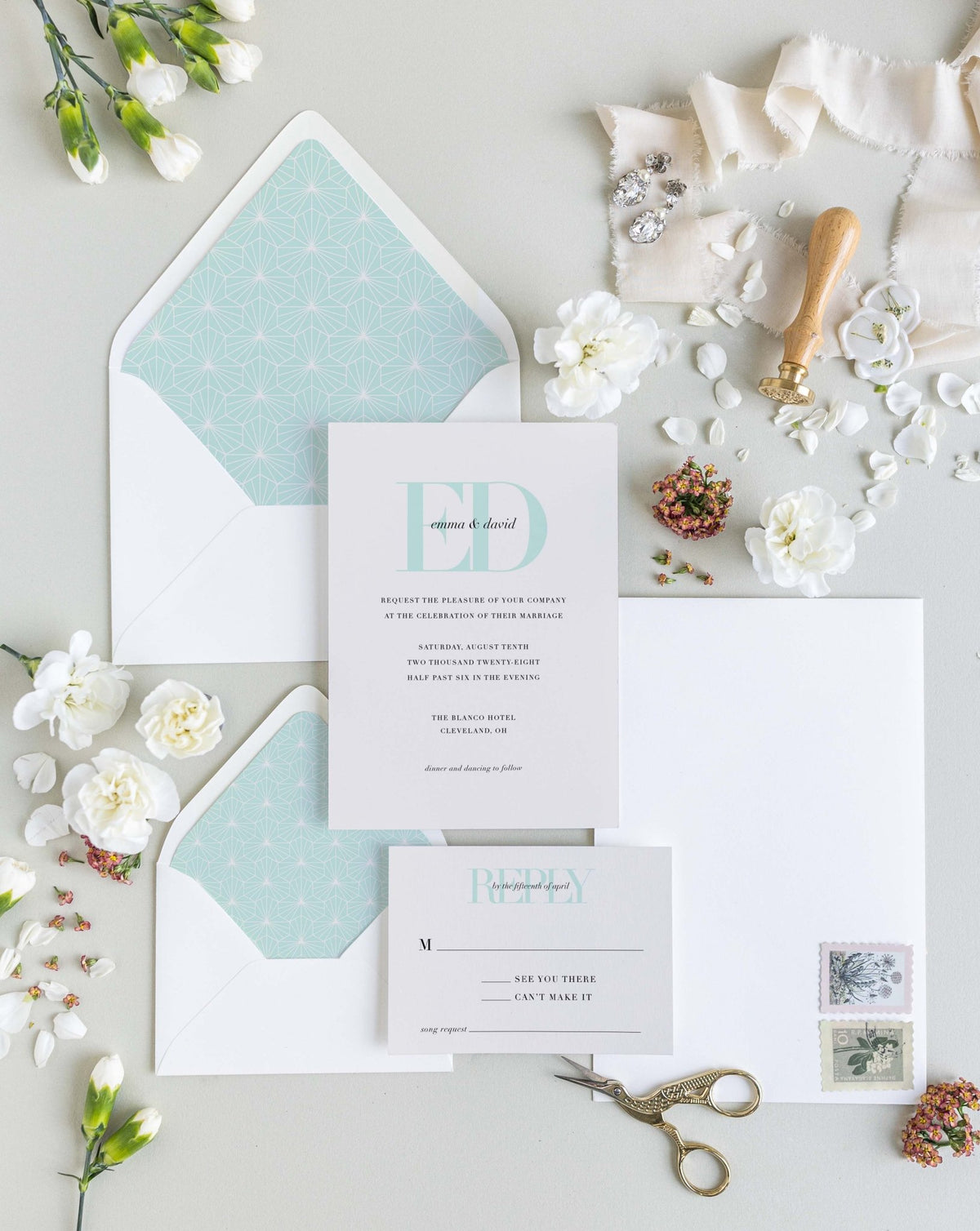 Emma wedding invitation suite by Blú Rose, cream invitation and reply card with a large mint 'ED' monogram, styled with mint geometric-lined envelopes, ribbon, and a wax seal