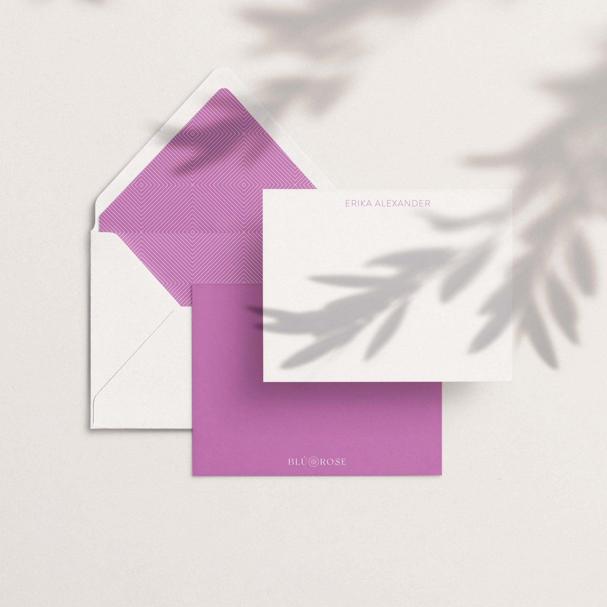 Flat lay showing a notecard and lavender envelope liner with minimalist arrow overlay on neutral background.