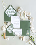 Fern wedding invitation suite by Blú Rose, invitation and response card with a green fern illustration, styled with fern-lined green envelopes, ribbon, and a wax seal