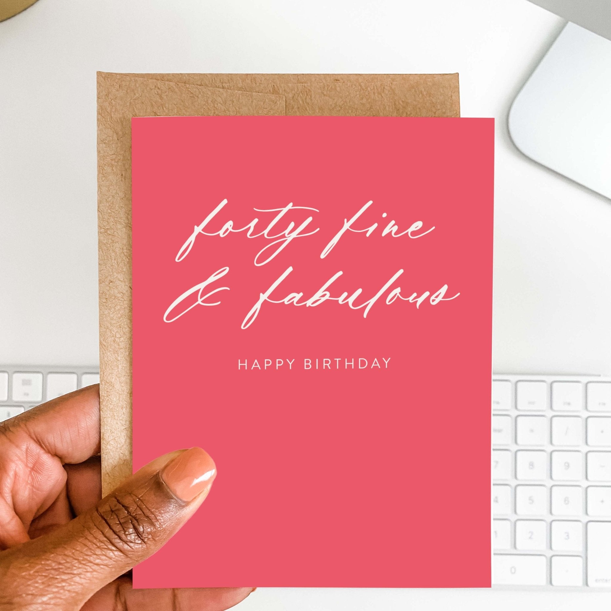 Forty Fine + Fab 40th birthday card by Blú Rose held in hand over a white desk with keyboard and kraft envelope