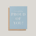 Freaking Proud of You encouragement greeting card by Blú Rose, dusty blue card with white proud of you text, shown with kraft envelope