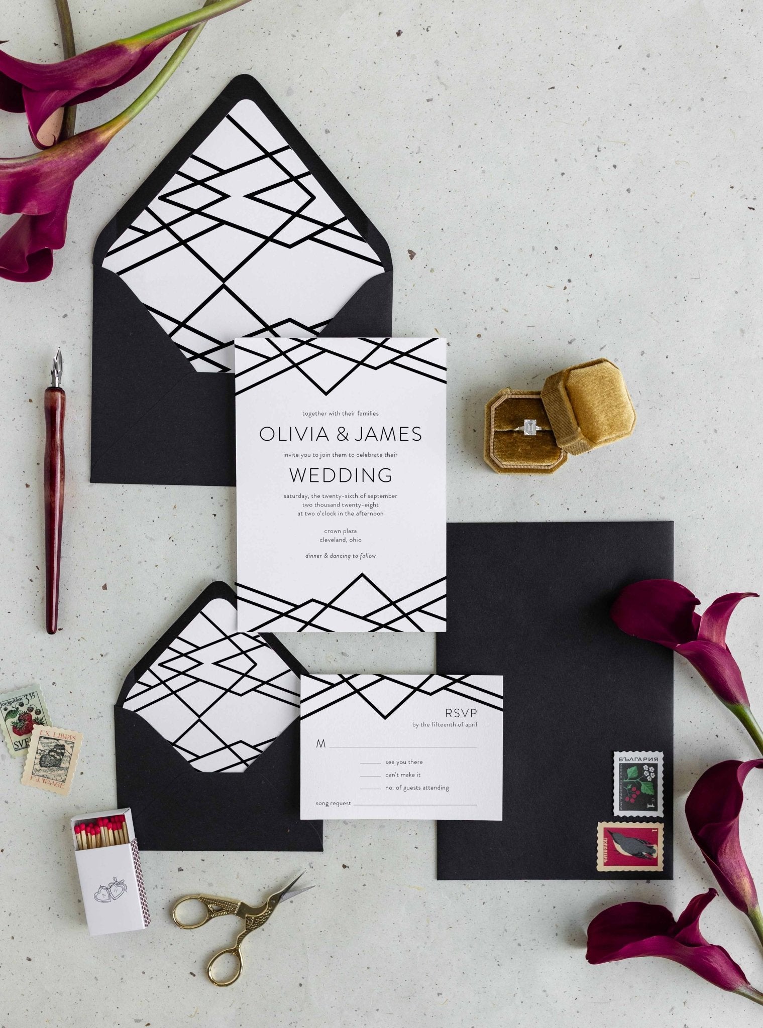 Geometric Art Deco wedding invitation suite by Blú Rose, invitation and RSVP card with black geometric line-work, styled with geometric-lined black envelopes and deep red calla lilies