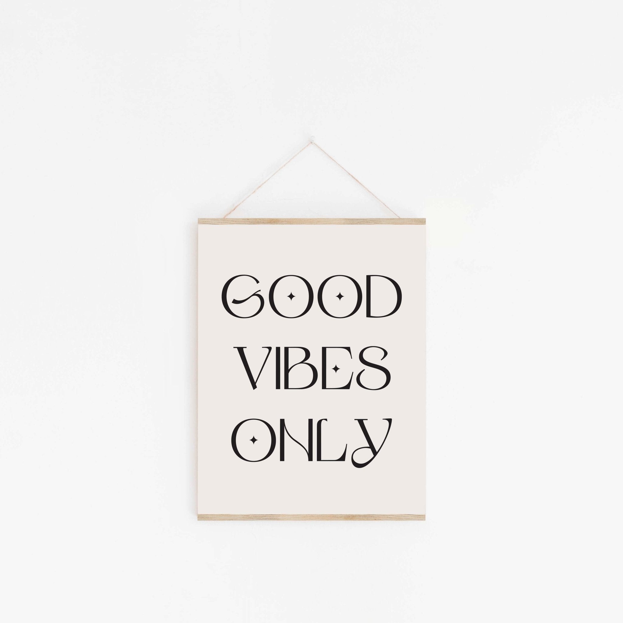 Good Vibes Only typography poster hanging from wooden hanger on off-white background