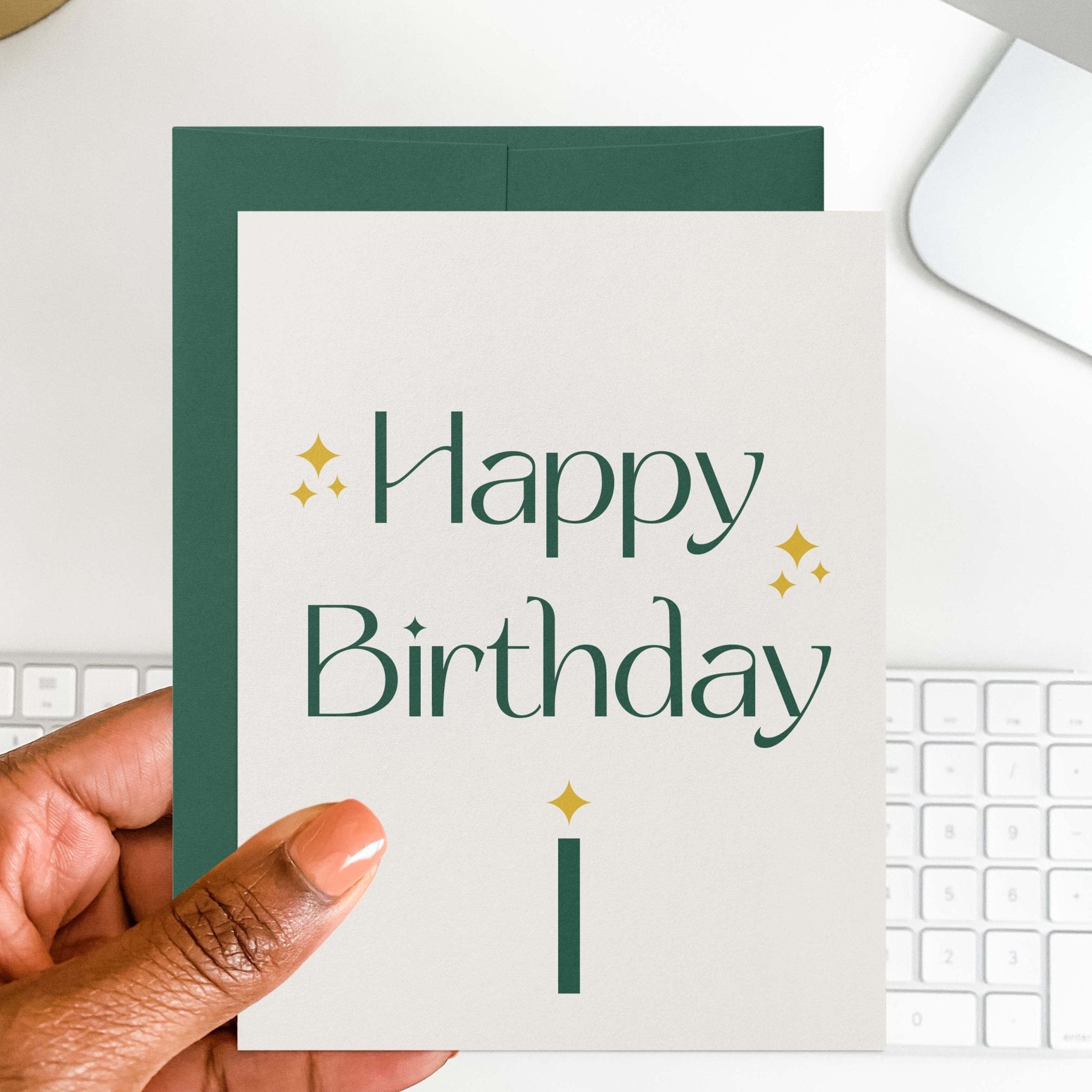 Green Sparkle Birthday card by Blú Rose held in hand over a white desk with keyboard and green envelope