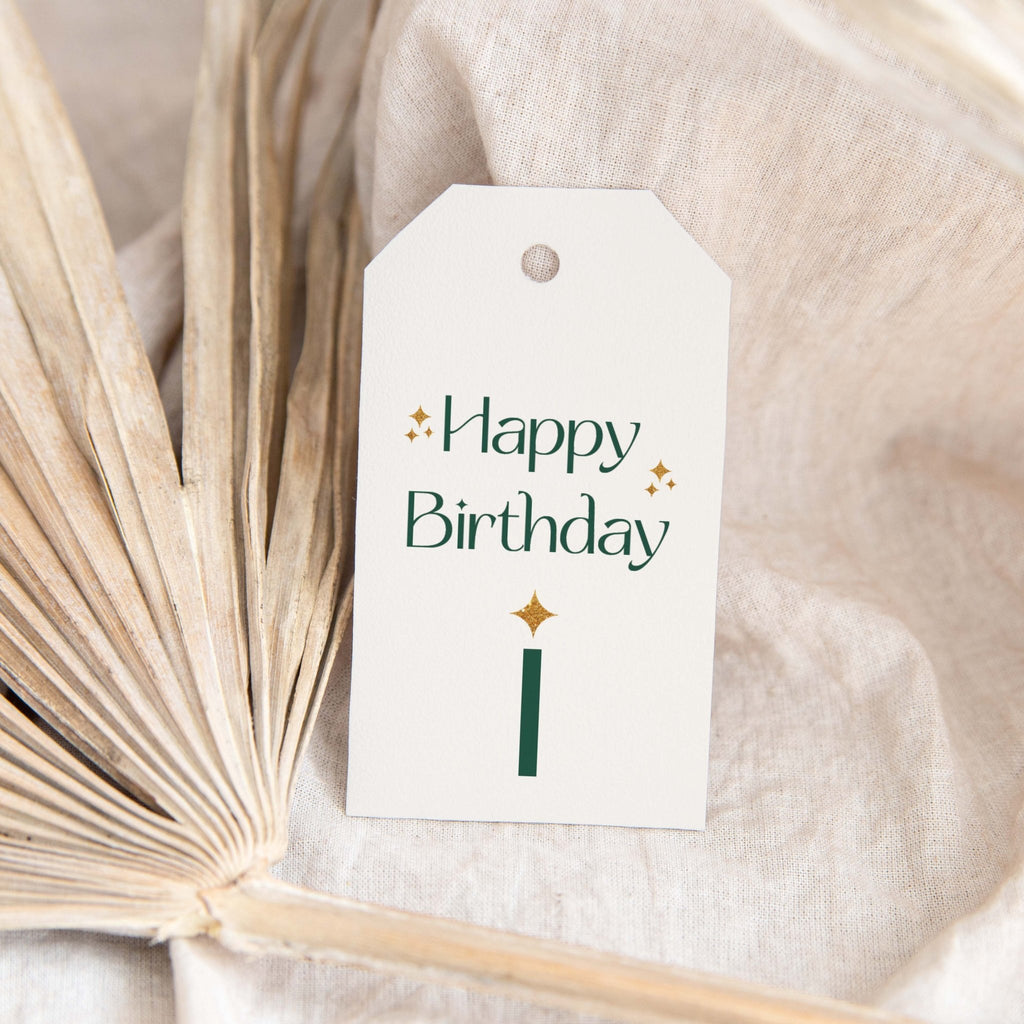 Green Sparkle Birthday gift tags by Blú Rose, white 'Happy Birthday' tag with green lettering and a gold sparkle candle styled on a dried palm leaf